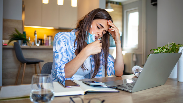 woman pulling down face mask to breathe better