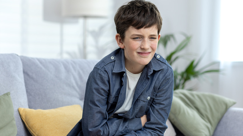 boy holding stomach and grimacing
