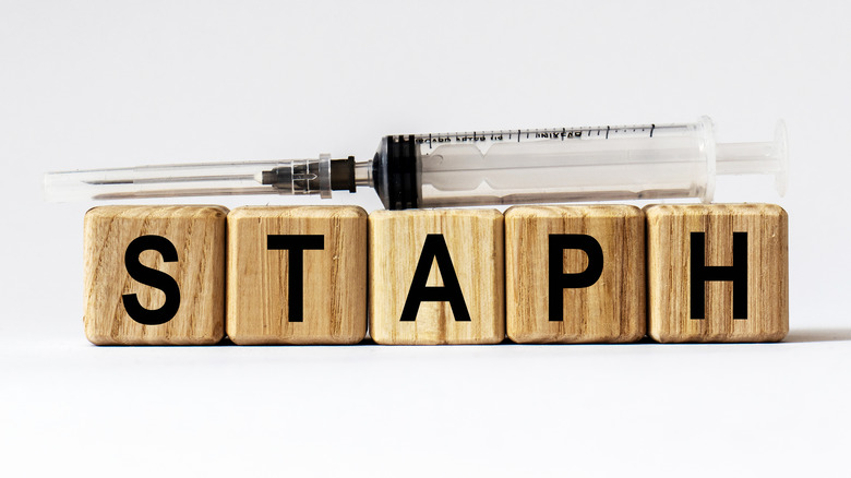 The word STAPH spelled out in wooden blocks with a syringe lying over the top