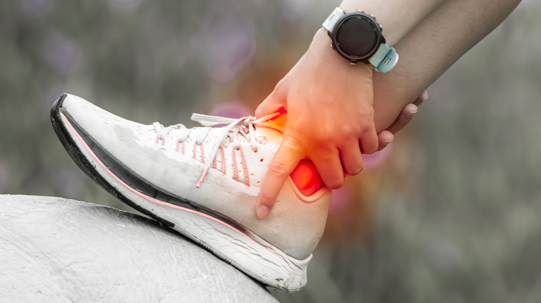 Runner holding their inflamed heel highlighted in red