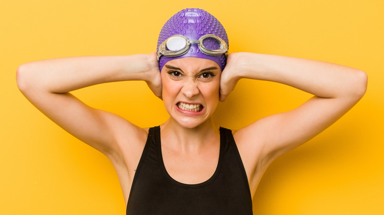 female swimmer holding her ears