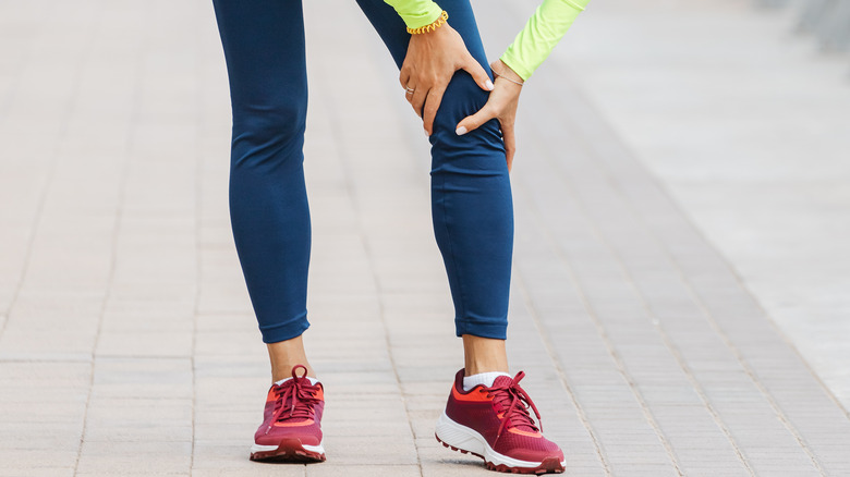 close up of woman in running clothes holding her knee 