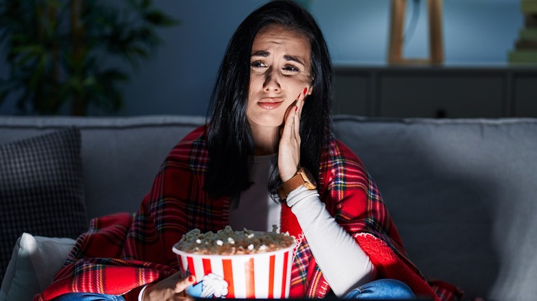 Woman with mouth pain holding popcorn