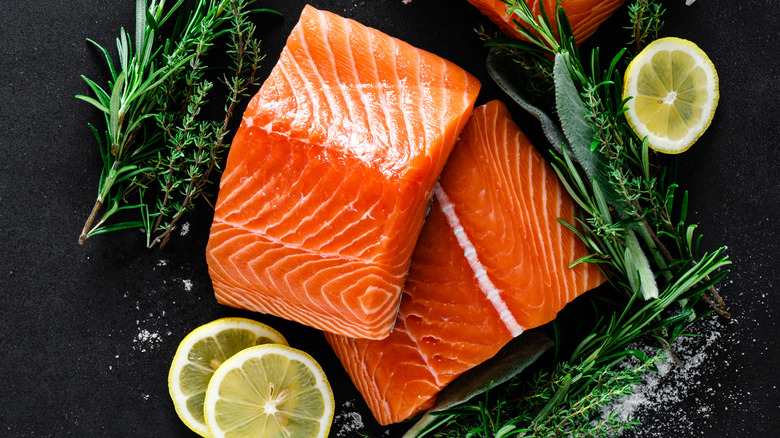 Salmon with lemon and herbs on black background