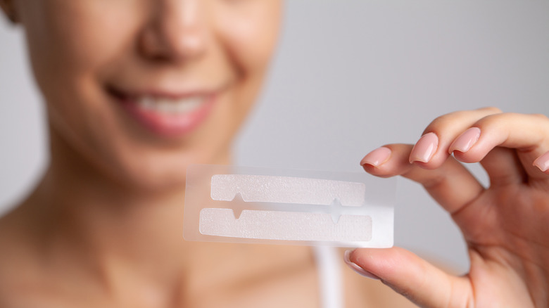 Woman holding whitening strip