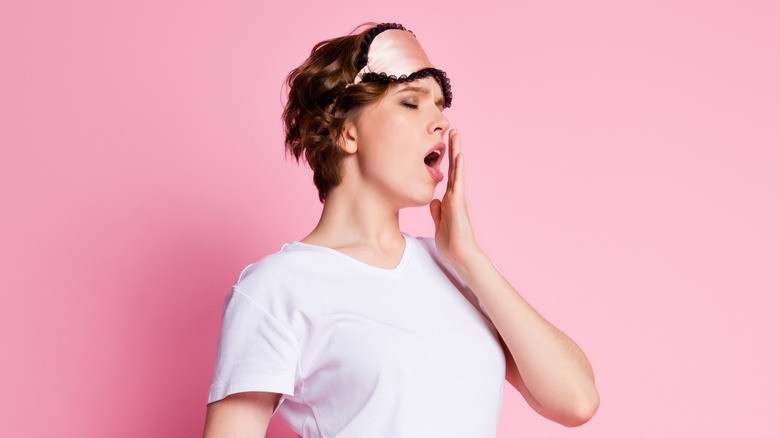 Woman yawning and walking in pajamas 