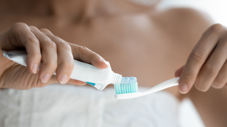 Hand squeezing toothpaste on toothbrush