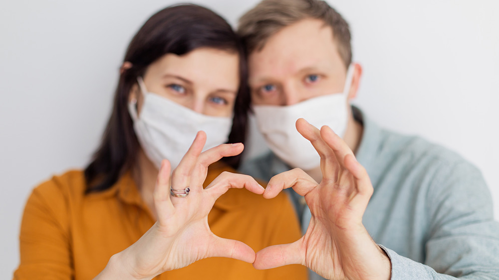 Masked couple forming heart symbol