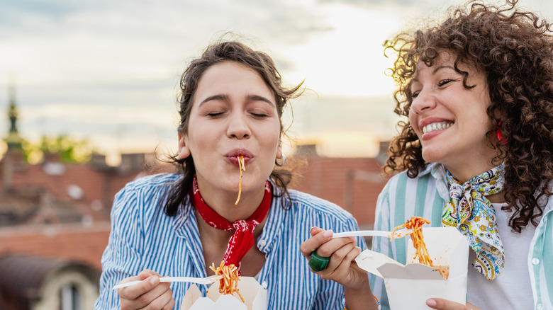 two friends enjoying pasta outdoors
