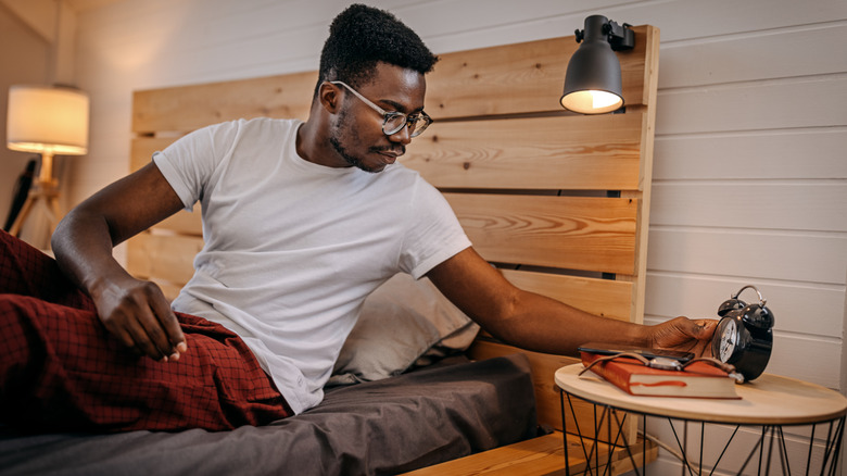 man setting his alarm before bed