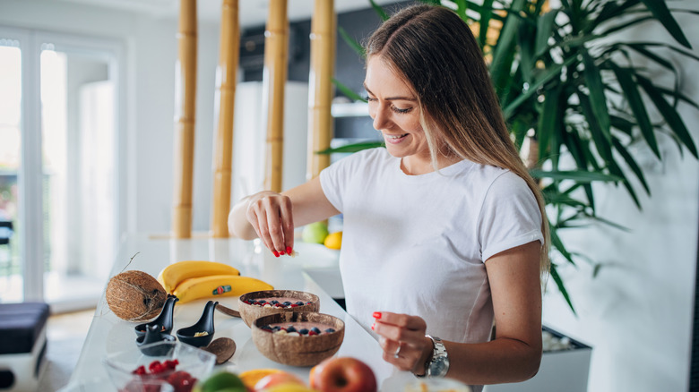 woman adding healthy ingredients to her breakfast bowl