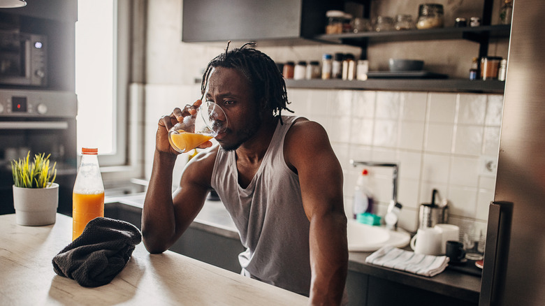 Man drinking glass of orange juice
