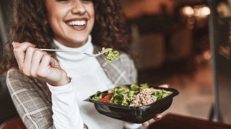 A woman eating a salad topped with tuna