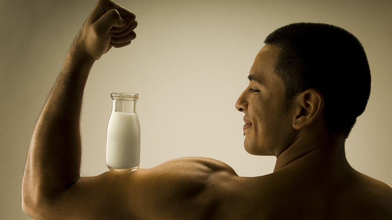 man balancing milk bottle on biceps