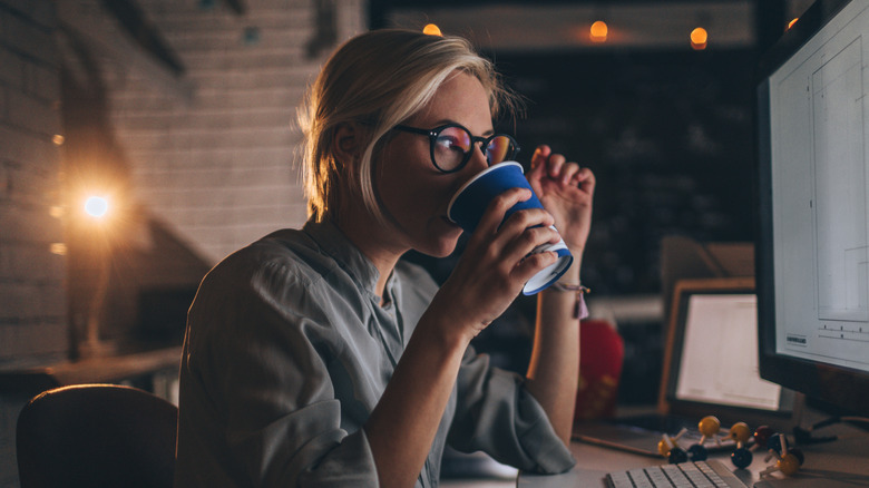 Young woman drinking coffee at night