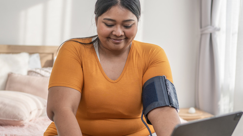 A woman checking her blood pressure in bed