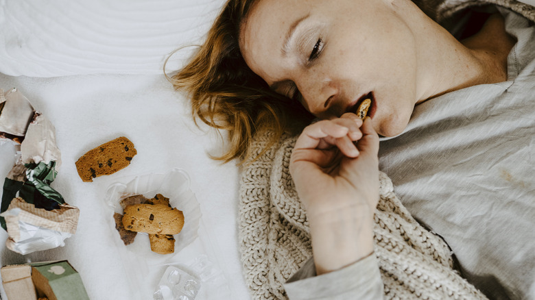 A woman lying in bed asleep with snacks around her