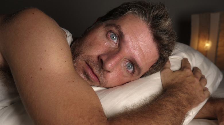 A man in bed with eyes wide open