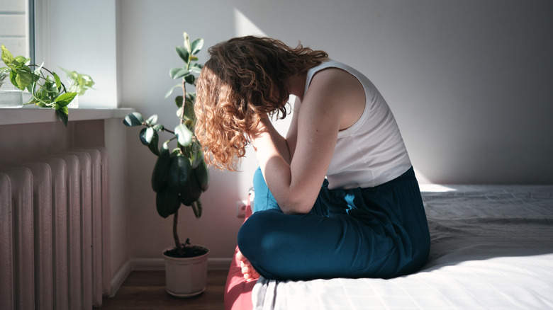 A woman sitting in bed with her face in her hands