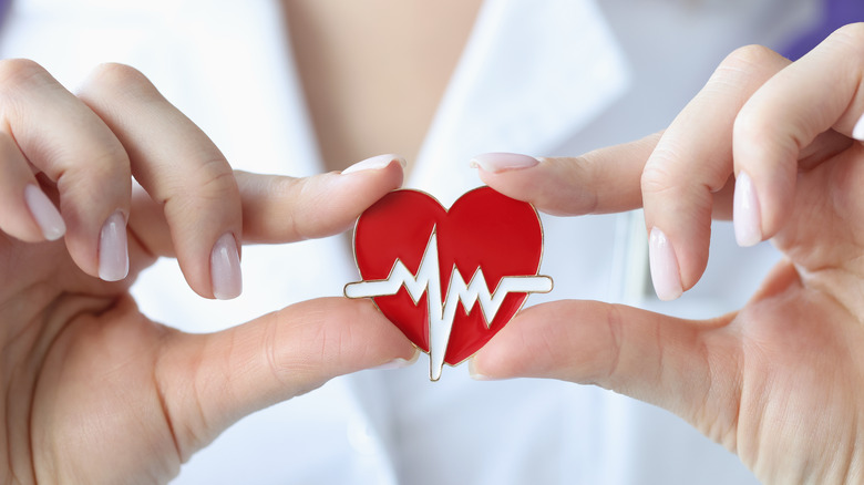 doctor holding red heart decal with electrical impulses