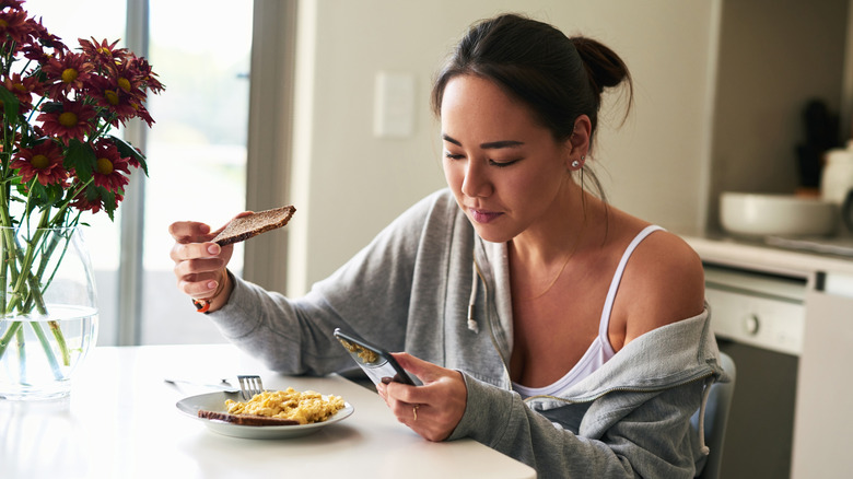 young woman eating plate of scrambled eggs and toast
