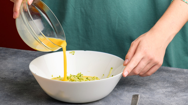 man pouring bowl of mixed raw eggs