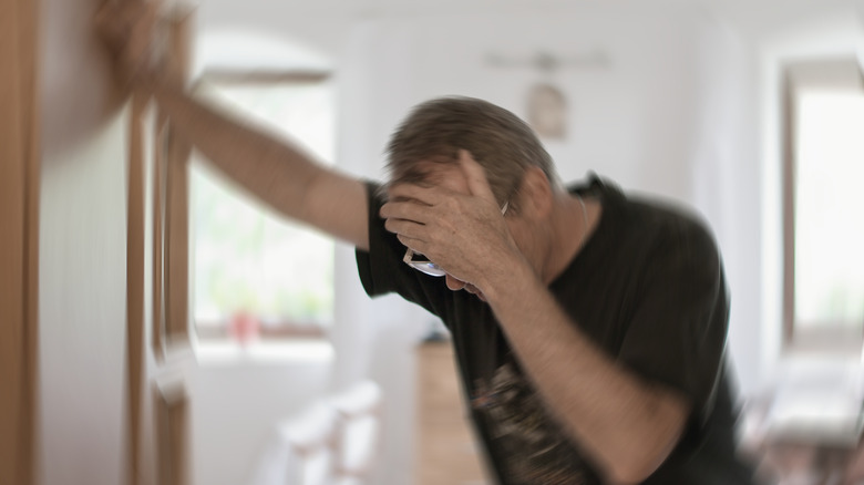 Dizzy man leaning on door