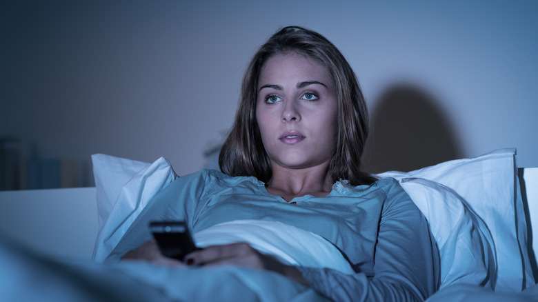 Woman in bed with TV on