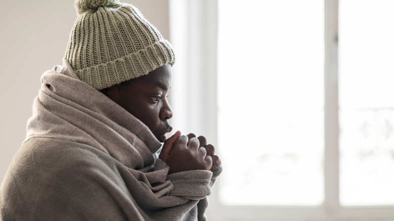 Young man heating hands with breath