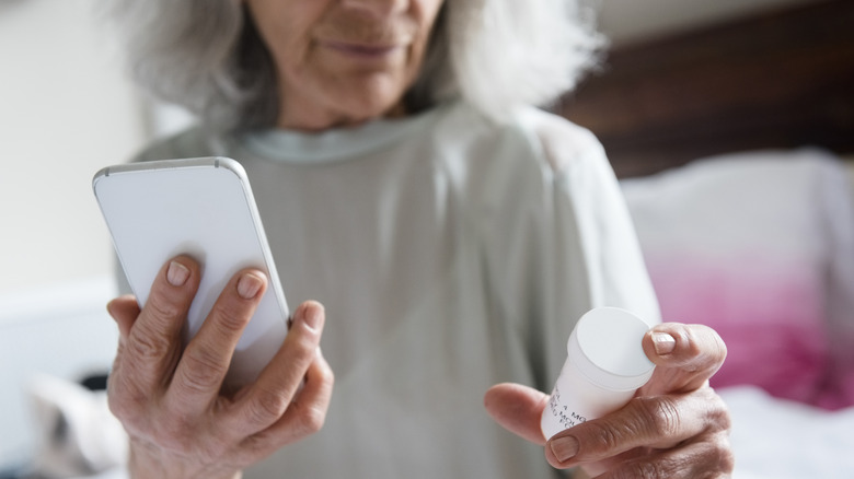 mature woman looking at prescription bottle