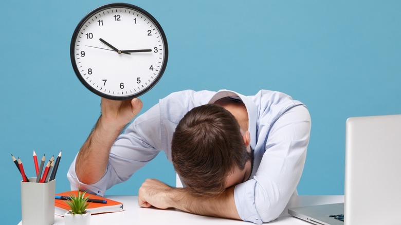 tired man at work holding clock