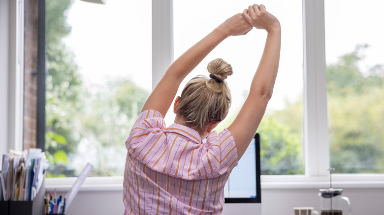 Woman sitting at desk and stretching her back