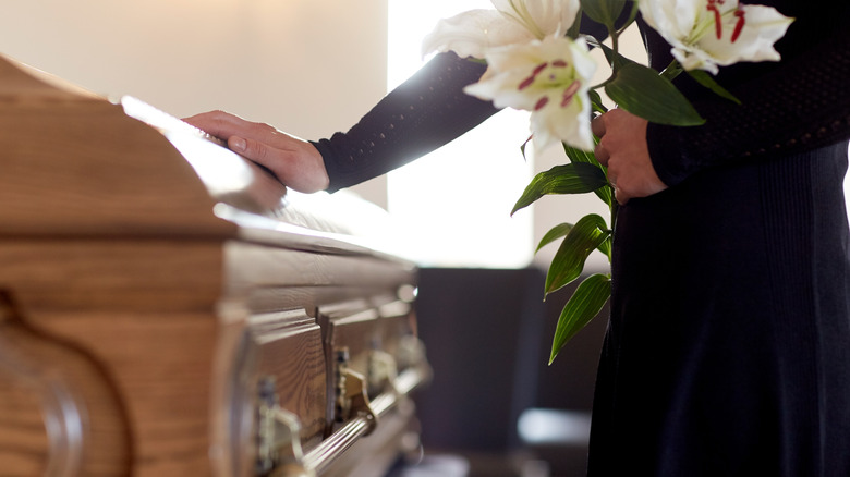 hand touching lid of coffin