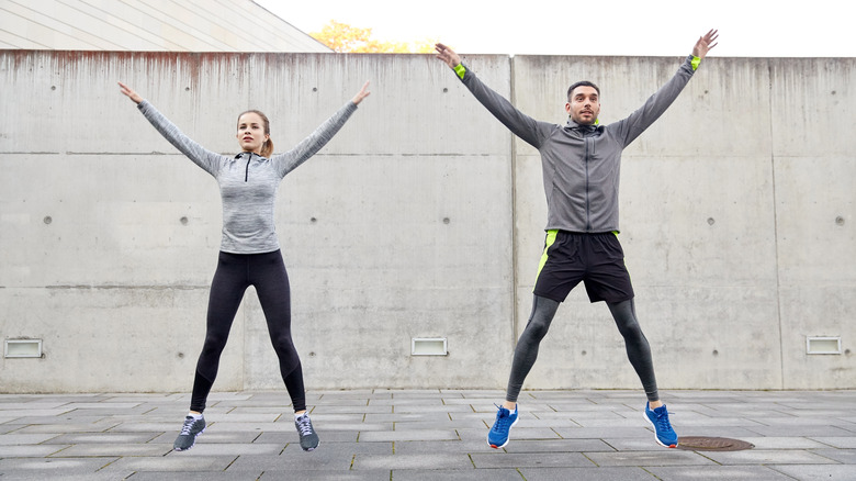 Two people doing jumping jacks