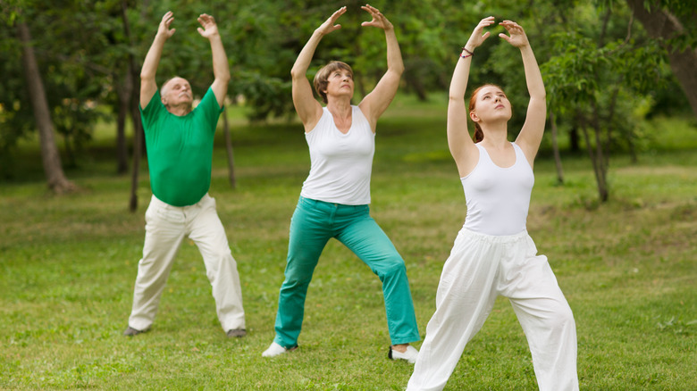 three people doing tai chi outside 