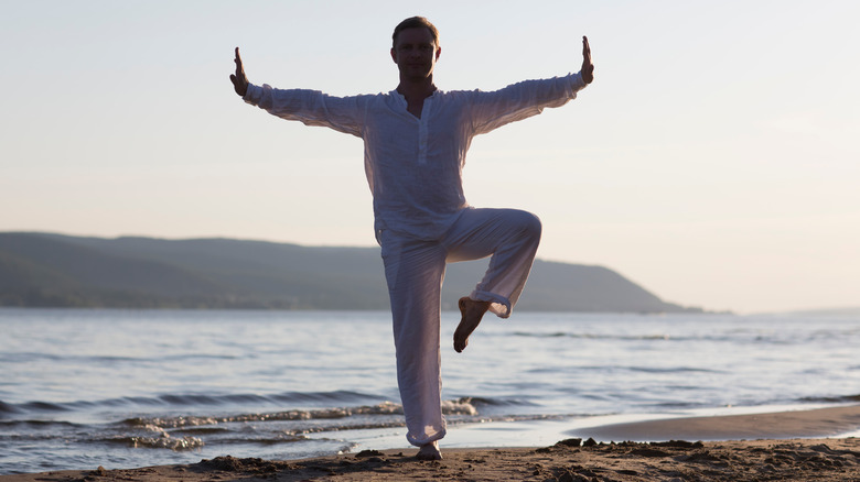 man practicing tai chi on a beach