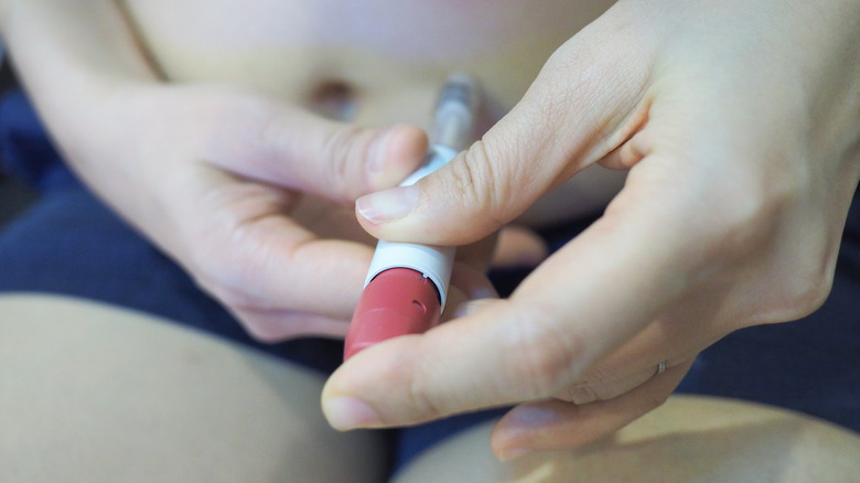 Woman giving herself injection of follicle stimulating hormone into her abdomen