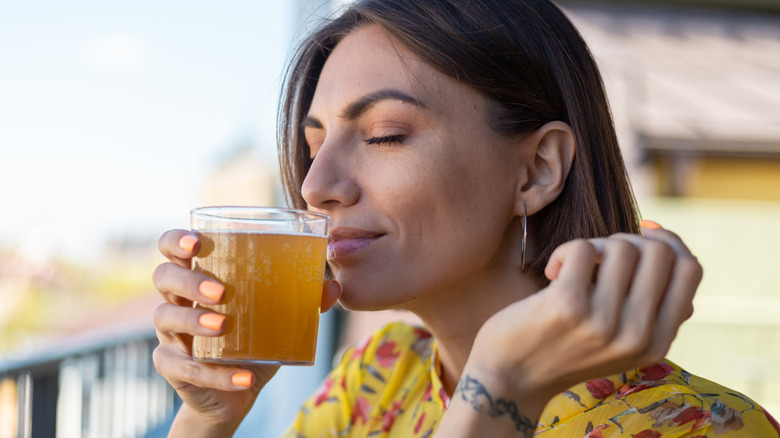 Woman drinking kombucha happy with eyes closed
