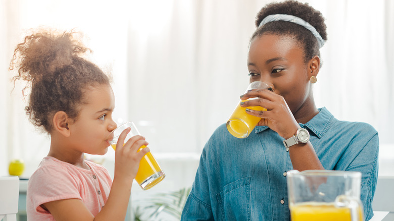 mother and daughter drinking orange juice