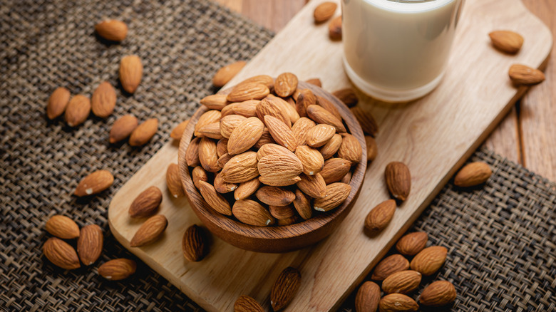 a bowl of almonds with a glass of milk