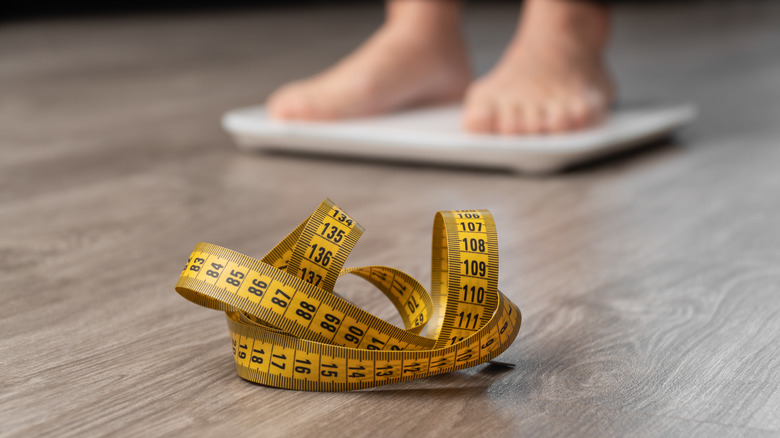 person on scale with measuring tape