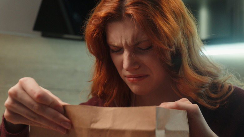 A disgusted woman looking at food in a paper bag