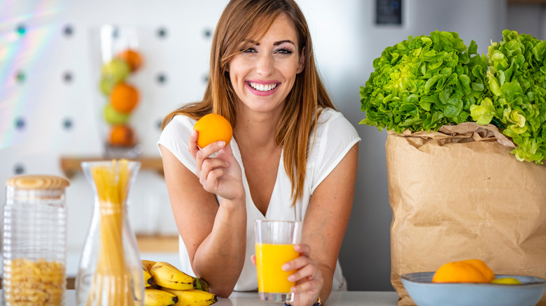 woman holding an orange and a glass of orange juice