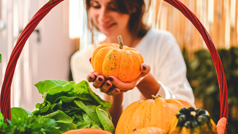 woman putting winter squash in a basket