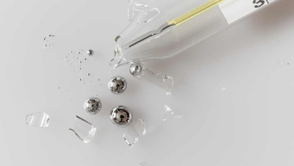 A broken glass thermometer that has spilled mercury droplets