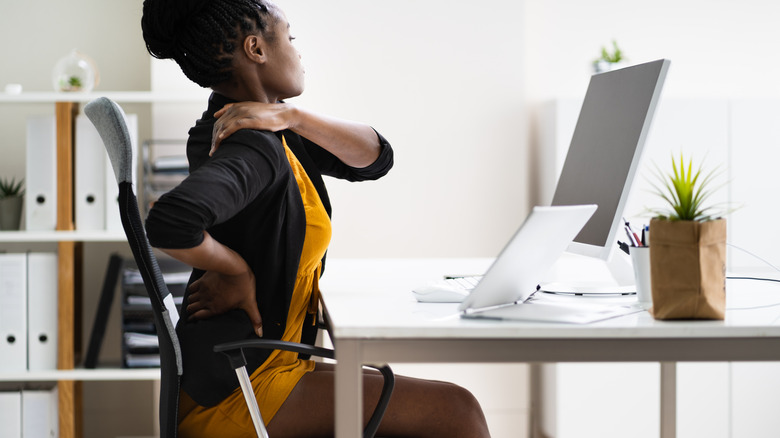 woman holding back and shoulder