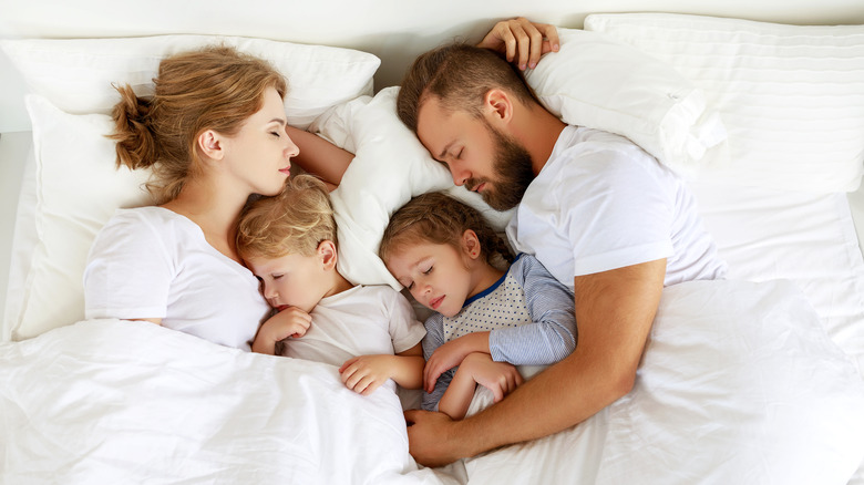 A family sleeps in bed