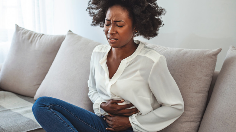 woman sitting grimacing holding belly