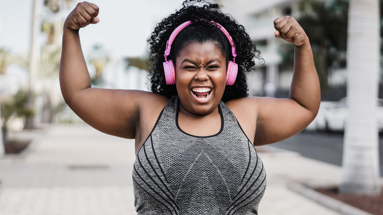 Women in headphones flexing arms