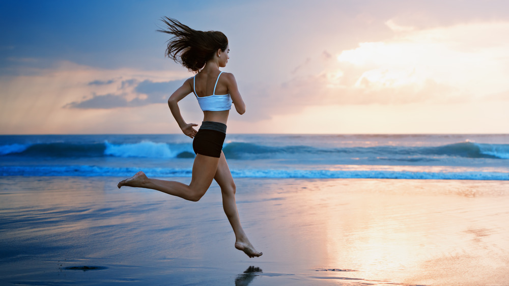 woman running barefoot on beach